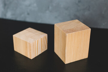 Natural mockup of wooden cubes for cosmetics on black and grey background.