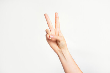 Woman's hand gesturing peace sign or victory on light grey background