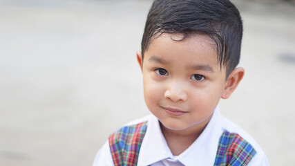 A cute Asian boy about 3 years old wearing a school uniform is happy to go to school.                