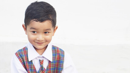 A cute Asian boy about 3 years old wearing a school uniform is happy to go to school.                