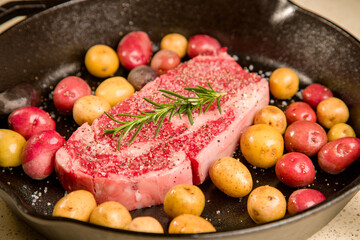 Red meat steak in a cast iron pan with potatoes