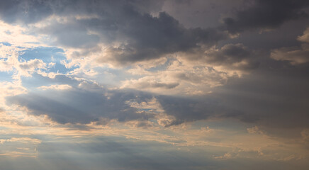 Naklejka na ściany i meble dramatic dark sky with rays and white clouds at sunset