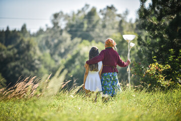 Grandmother and granddaughter stand in the field and look into the distance