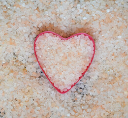 Himalayan salt in the shape of a heart top view. Pink salt crystals. Healthy food concept