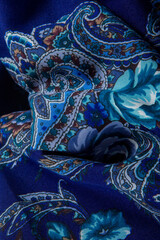 top view closeup on part of folded blue paisley pattern on dark cotton shawl
