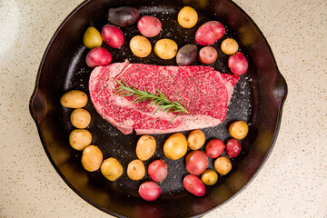 Red meat steak in a cast iron pan with potatoes