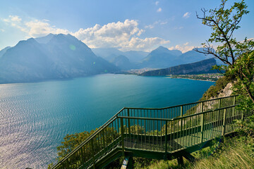 Panoramic view on Lake Garda from the Busatte-Tempesta trail near Nago-Torbole with the iron staircase,  Torbole  town surrounded by mountains in the summer time,Italy