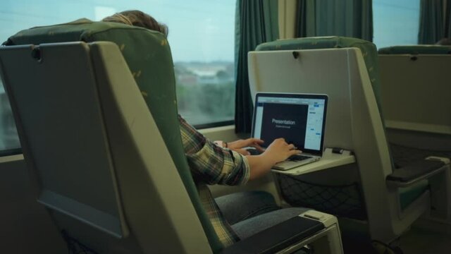 Side shot of young woman in train sit by window and work on presentation project on laptop. Concept student or employee get ready before work hours or school. Female developer write code or text notes