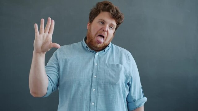 Slow motion of annoyed young man showing talking hand gesture and saying bla bla bla then closing ears feeling tired of conversation. People and communication concept.