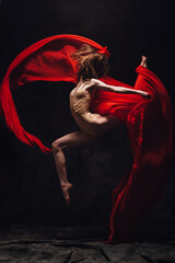 ballerina jumping with red cloth in studio