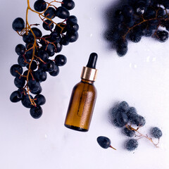 Cosmetics with grapes. Glass bottle with oil next to ripe grapes