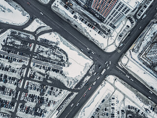 Drone aerial view of the intersection of streets or road highways in a busy car traffic modern city at winter time