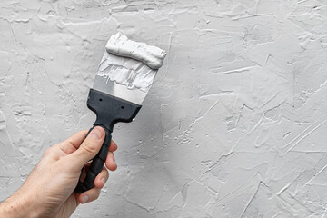 Applying putty or plaster to a vertical wall in a renovated house with a spatula or trowel.