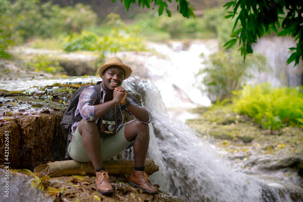 Wall mural african traveler man sitting and relaxing freedom with waterfall