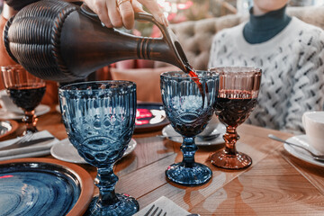 Red wine is poured from vintage clay jugs into retro glasses in an authentic Georgian restaurant - obrazy, fototapety, plakaty