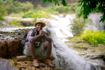 African traveler man sitting and relaxing freedom with waterfall