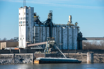 Grain elevator terminal spout loading grain corn into bulk dry cargo barge on Mississippi River, food, crops, harvest, export, transport, marine, maritime, silos, storage containers - obrazy, fototapety, plakaty