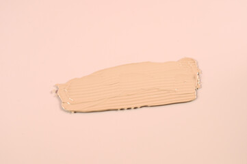 Close up of smear of foundation on pastel pink background