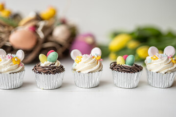 cute colorful spring easter egg shape cake tartlet muffin cupcake with yellow tulips easter concept 