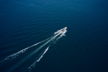 Top view of a white boat sailing to the blue sea. Large speed boat moving at high speed side view