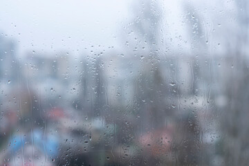 Drops of water on the window pane against the background of the city.