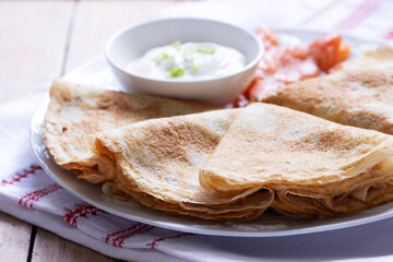 Thin pancakes with salmon and sour cream on a light background. Rustic style.