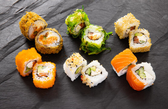 Different sets of colorful sushi on black stone background