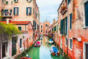 Fototapeta na wymiar Scenic canal with old medieval architecture and boats in Venice, Italy. Famous travel destination