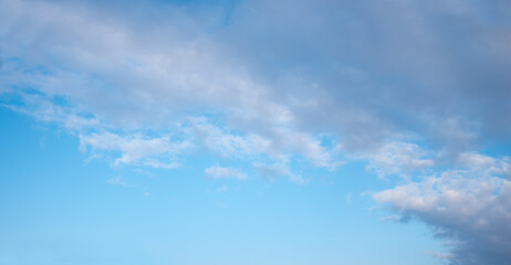 sky background with grey clouds in the upper half and blue copy space