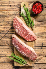 Raw rump cap steak on a chopping Board. wooden background. Top view