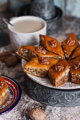 Assorted baklava. A Turkish ramadan arabic sweet dessert on a decorative plate, with coffee cup in the background. Middle eastern food baklava with nuts and honey syrup