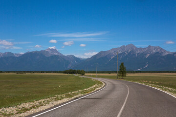 Naklejka premium The road goes into the distance. Mountains in the background. Landscape with a horizon. Summer sunny day. Traveling around the country.