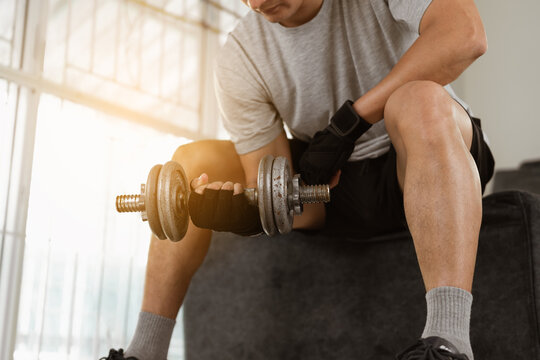 Sport man doing dumbbell biceps curl exercise workout in home.