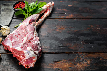 Whole raw goat leg with herbs and spices. Farm meat. Dark wooden background. Top view. Copy space