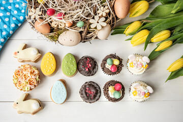 Fototapeta na wymiar cute colorful spring easter egg shape cake tartlet muffin cupcake with yellow tulips easter concept 