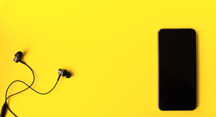 Headphones and smartphone on yellow background. Space for text. Copy space. Flat lay. 