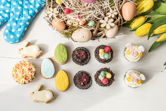 cute colorful spring easter egg shape cake tartlet muffin cupcake with yellow tulips easter concept - Powered by Adobe