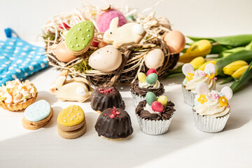 cute colorful spring easter egg shape cake tartlet muffin cupcake with yellow tulips easter concept 