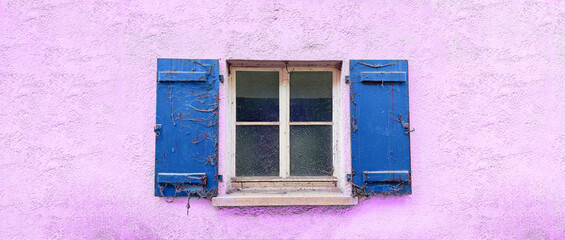 Panoramabild - Fenster mit blauen alten und mit Spinnweben behangenen Fensterläden. Die Hausfassade ist rosarot.