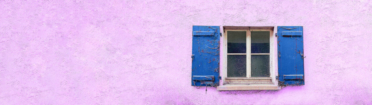 Fenster mit blauen alten und mit Spinnweben behangenen Fensterl&auml;den. Die Hausfassade ist rosarot.