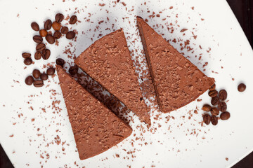 A piece of chocolate cake on a white plate on a wooden background