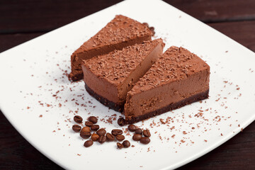 A piece of chocolate cake on a white plate on a wooden background