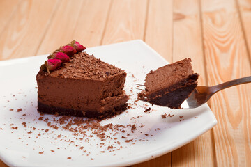 A piece of chocolate cake on a white plate on a wooden background