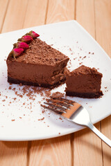A piece of chocolate cake on a white plate on a wooden background