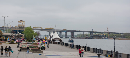 Two bridges, construction of new and repair old. Citizens walk on the waterfront