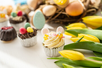 cute colorful spring easter egg shape cake tartlet muffin cupcake with yellow tulips easter concept 