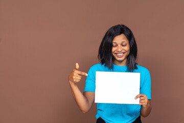 smiling pretty young black woman holding an empty sign and pointing to it
