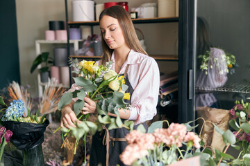 Photo of successful modern florist wearing apron making picture of flower, creating beautiful...