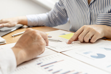 Two businessmen are examining the information in the company's financial documents provided by the finance department, they brainstorm to develop the company to further growth. Financial concept.