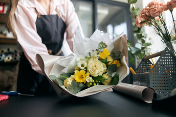Portrait of successful modern florist wearing apron, creating beautiful bouquet of colorful...